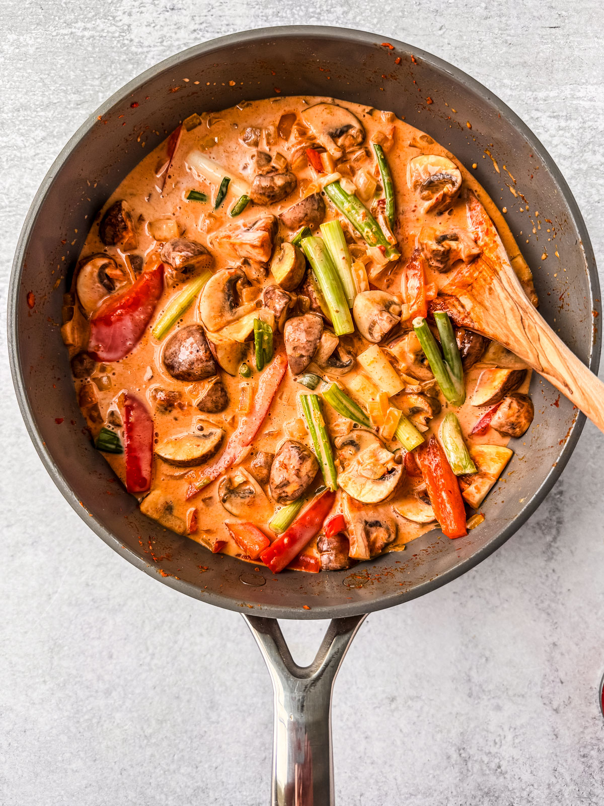 Creamy coconut curry with vegetables well mixed in a pan.
