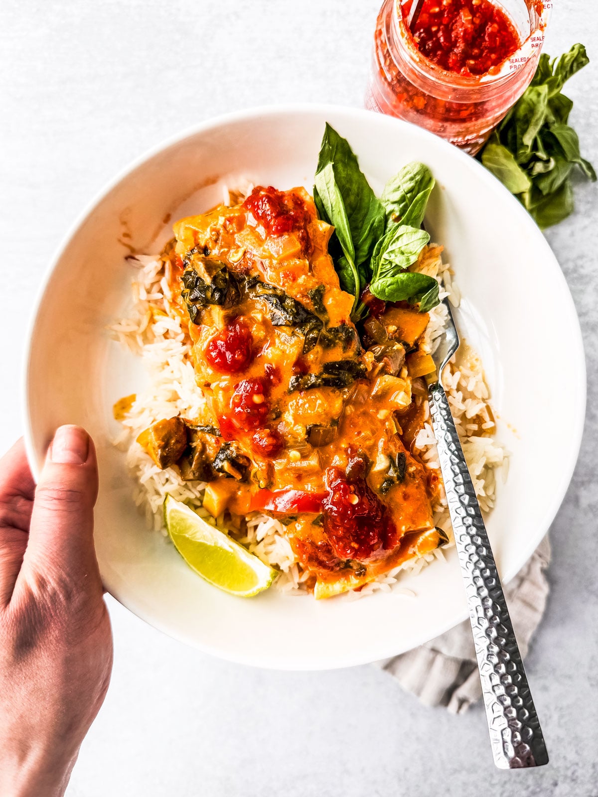 Fillet of curry salmon with coconut milk over a bed of basmati rice served with fresh basil and a lime wedge.
