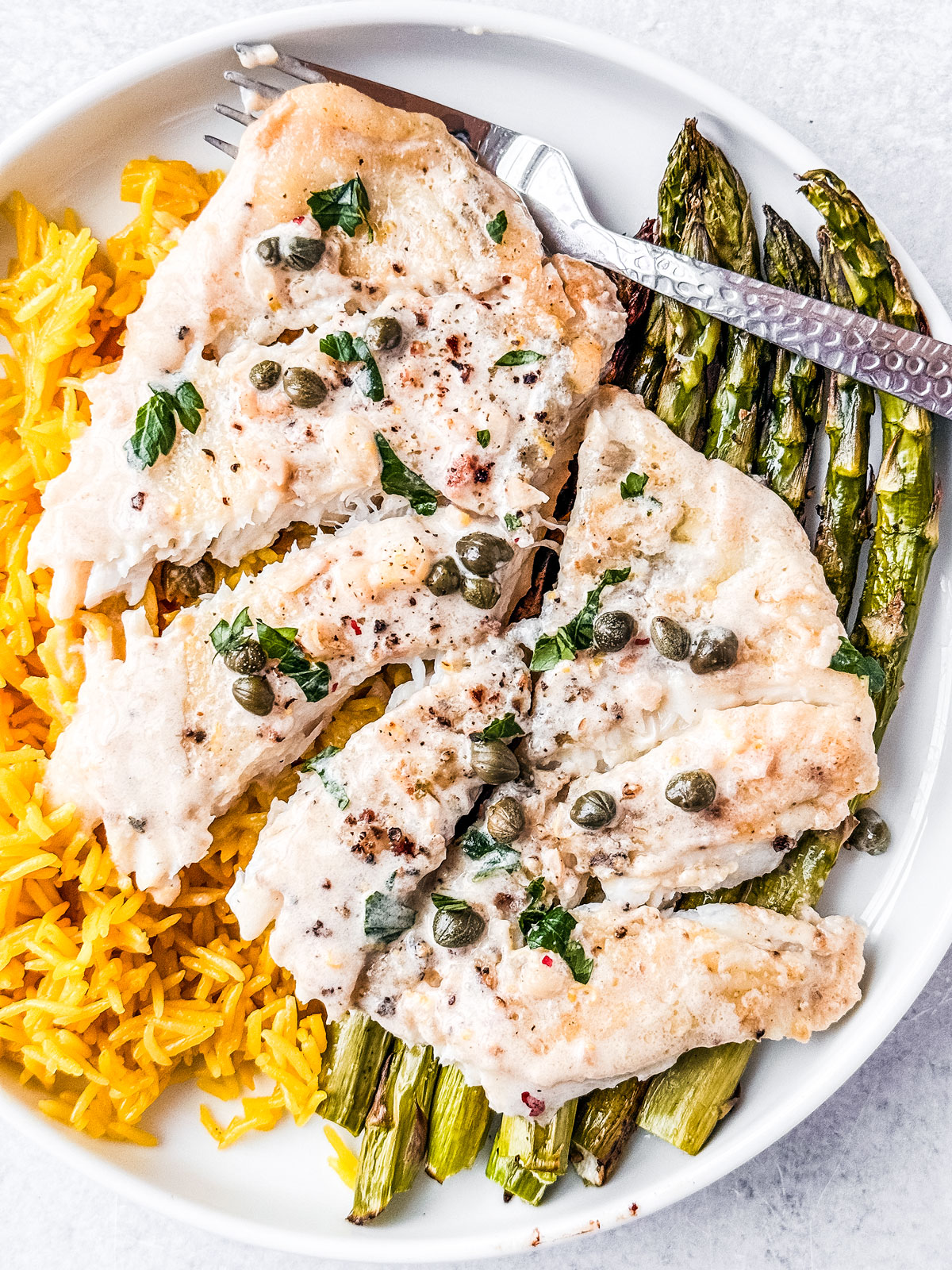Flaked flounder fillet over rice and asparagus.