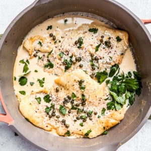 Skillet with flounder fillets in creamy lemon caper sauce.