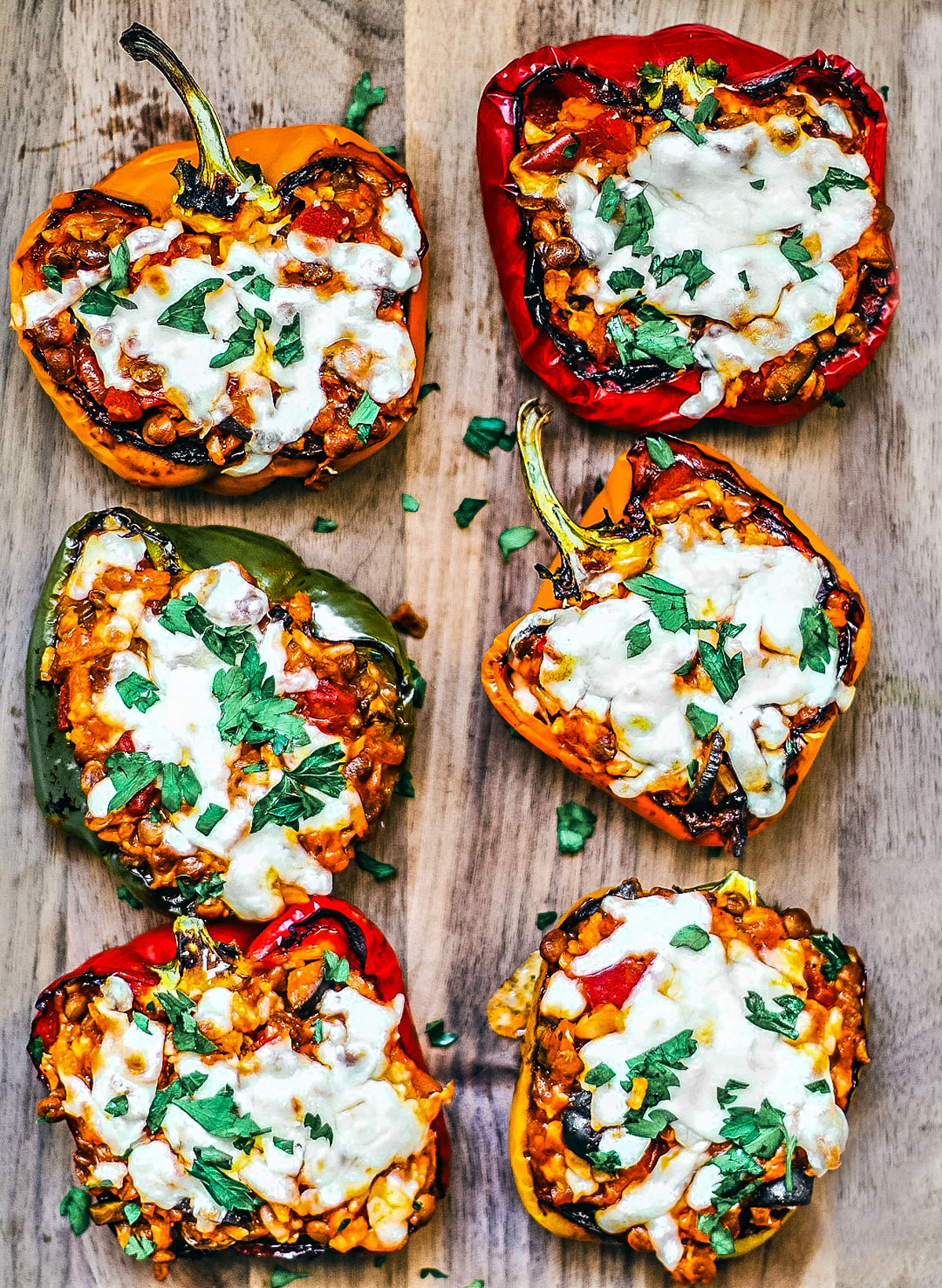Cheesy stuffed vegetarian peppers on a wooden serving board.