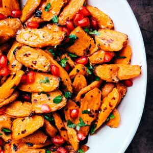 hot honey roasted carrots garnished with pomegranate arils and parsley.