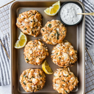 Jumbo lump crab cakes on a serving tray with side dish of yogurt sauce.