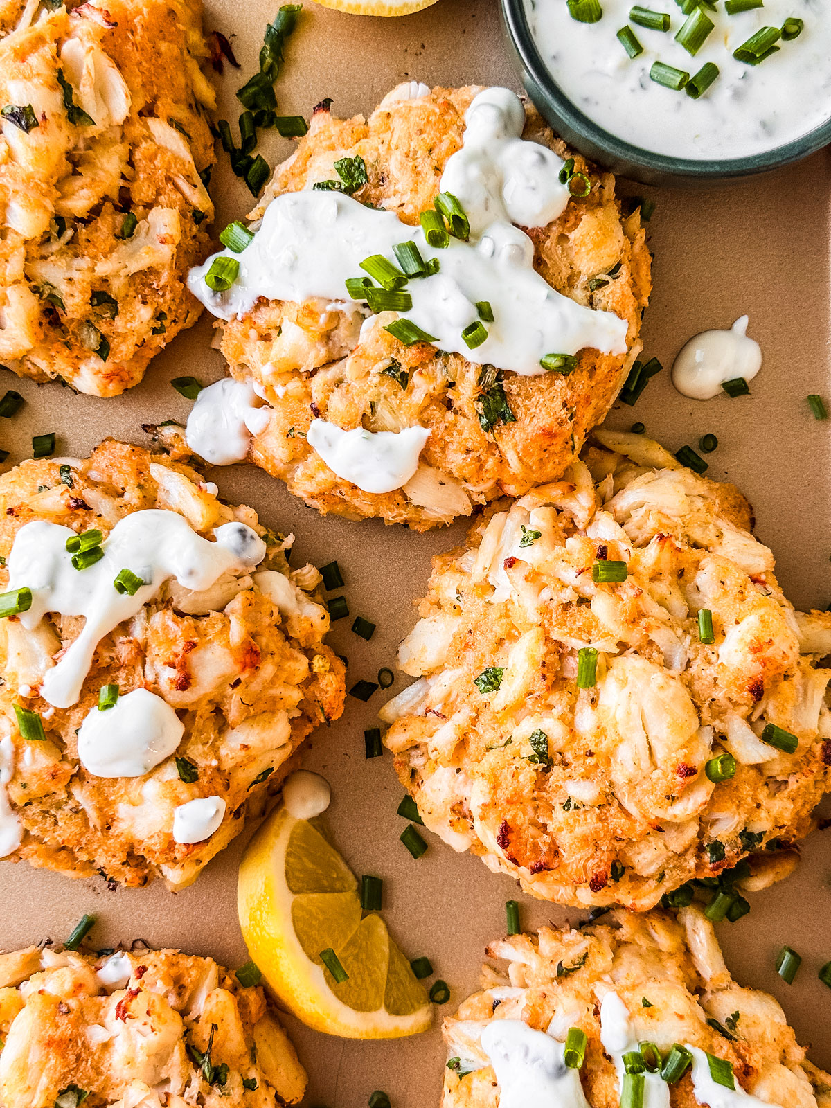 Close up of cooked crab cakes with yogurt sauce drizzled on top.