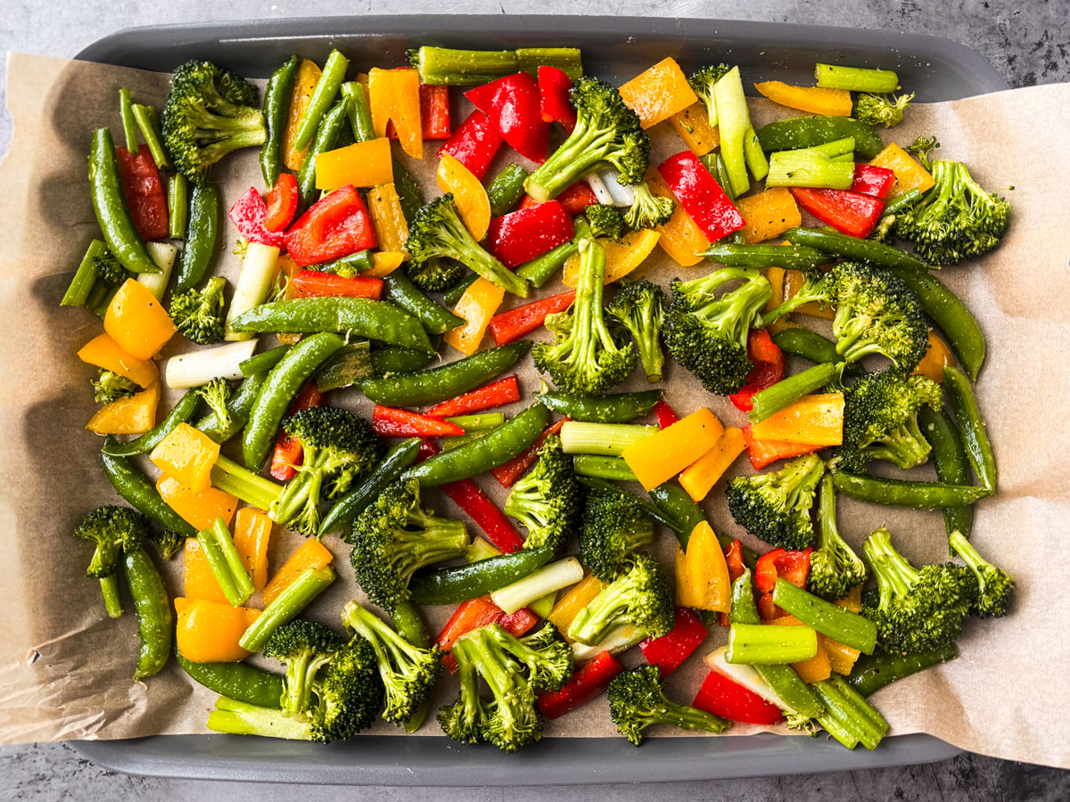 Colorful veggies spread out on a baking sheet.