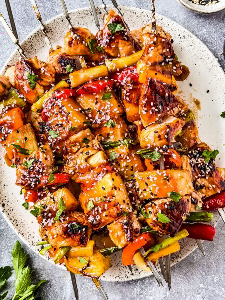 Grilled pineapple chicken kabobs with teriyaki sauce on a serving platter.