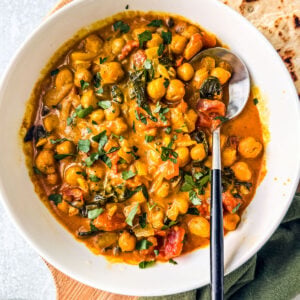 Bowl of chickpea curry with a piece of naan.