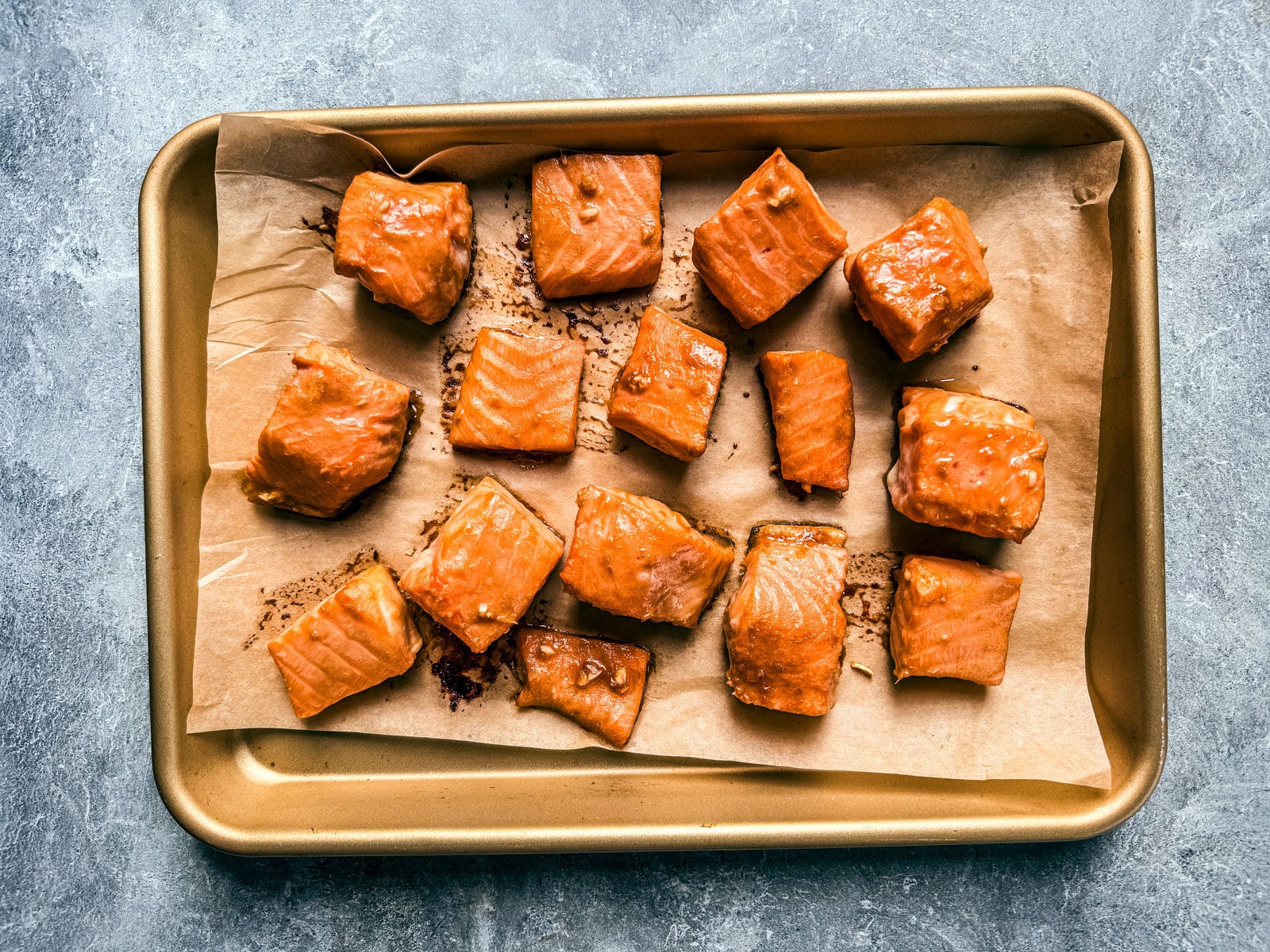 Cooked salmon bites on a parchment-lined baking sheet.