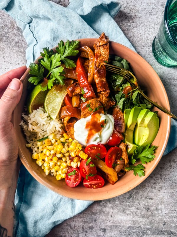 Chicken fajita bowl topped with fresh veggies.