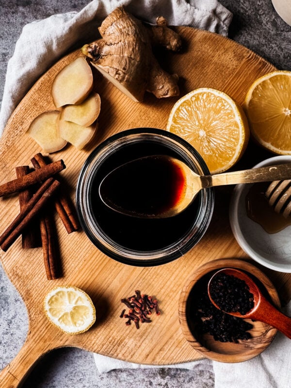 Overhead shot of elderberry syrup and ingredients on a wooden serving board.