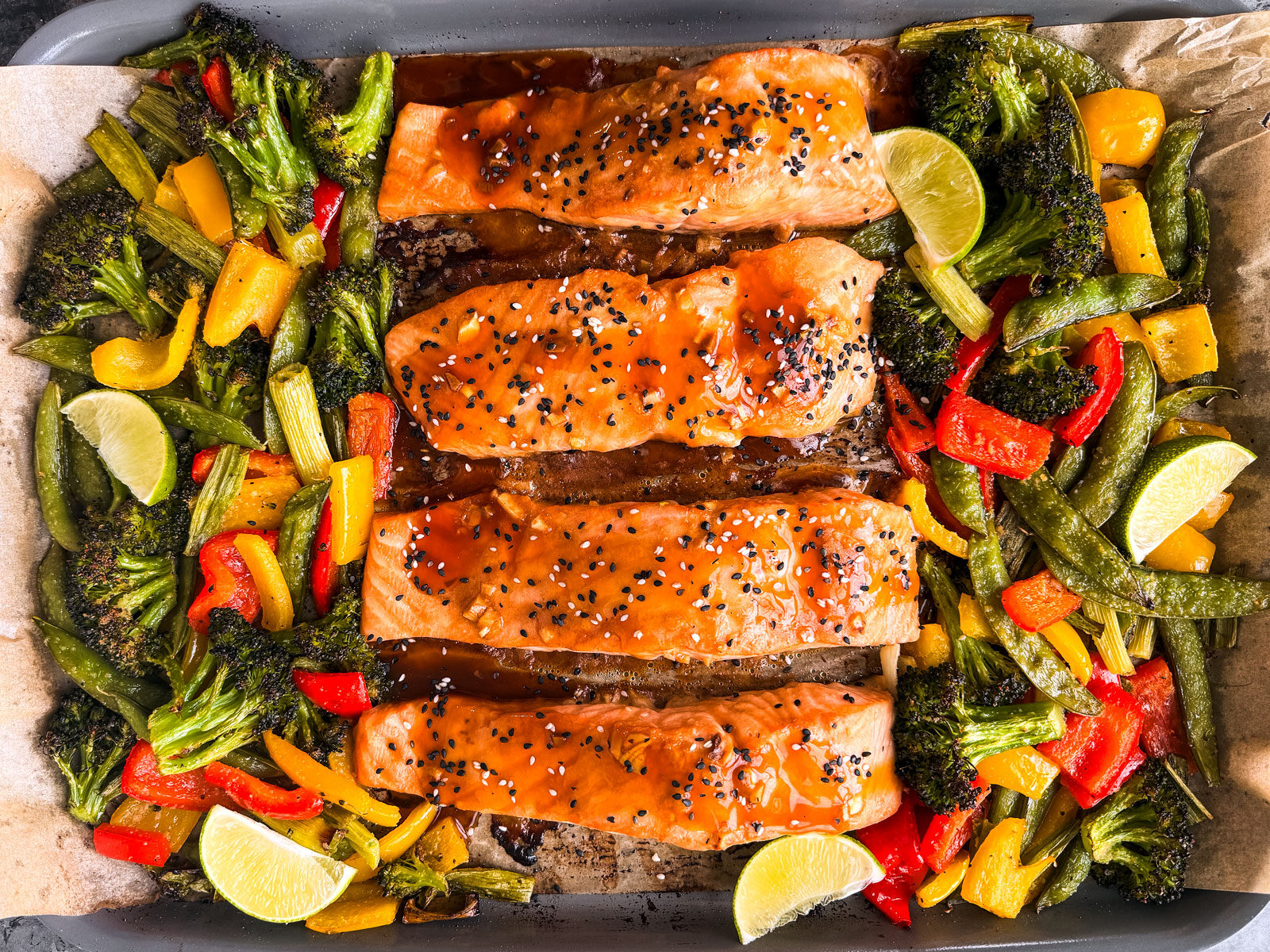 Cooked fish fillets on a sheet pan with roasted vegetables.