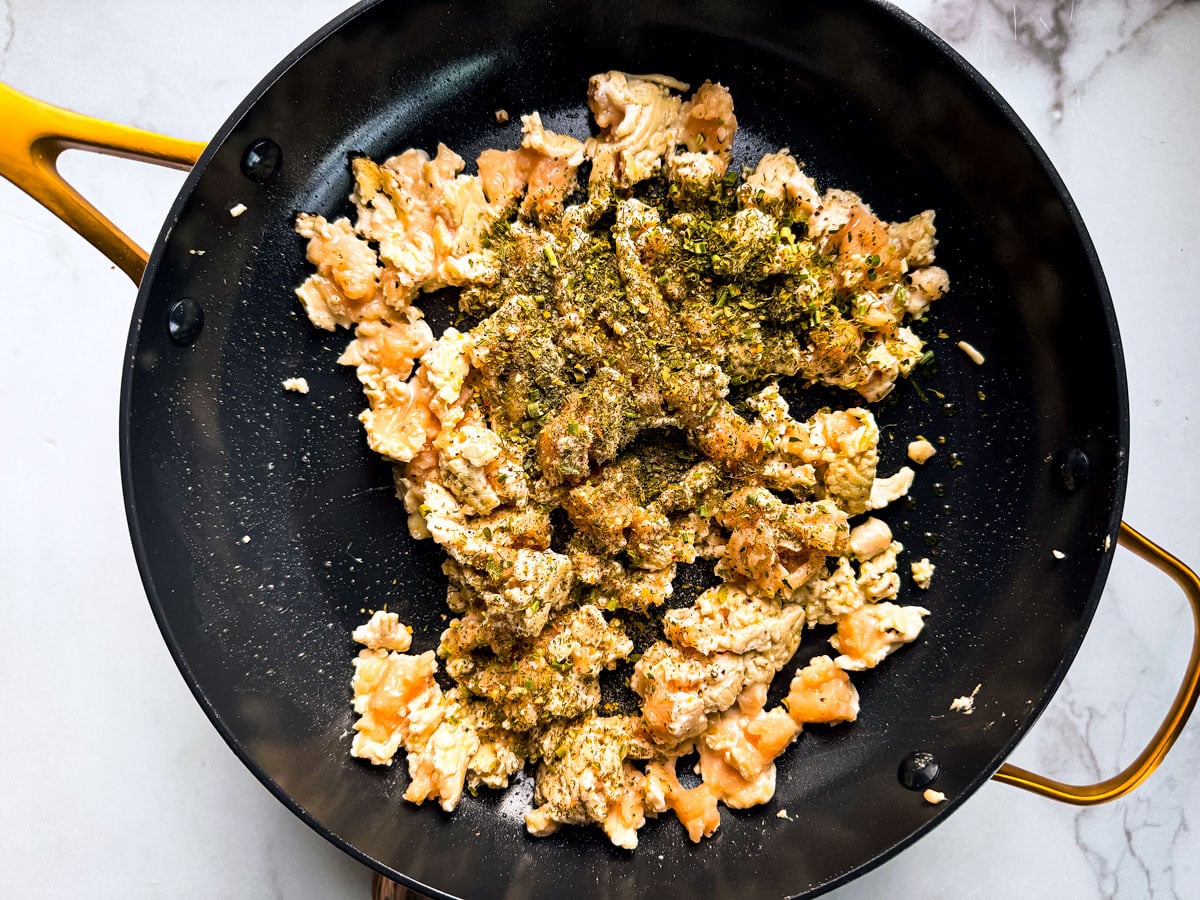 Pan of half-cooked ground chicken with Ranch seasoning  scattered on top.