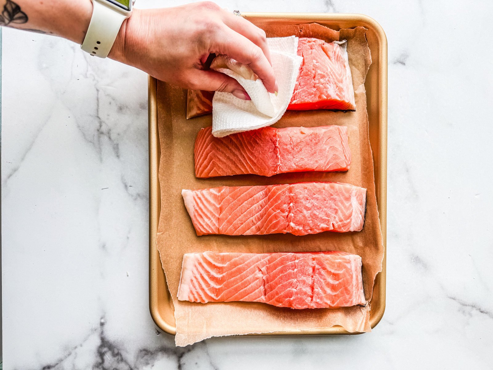 Hand blotting uncooked salmon fillets.