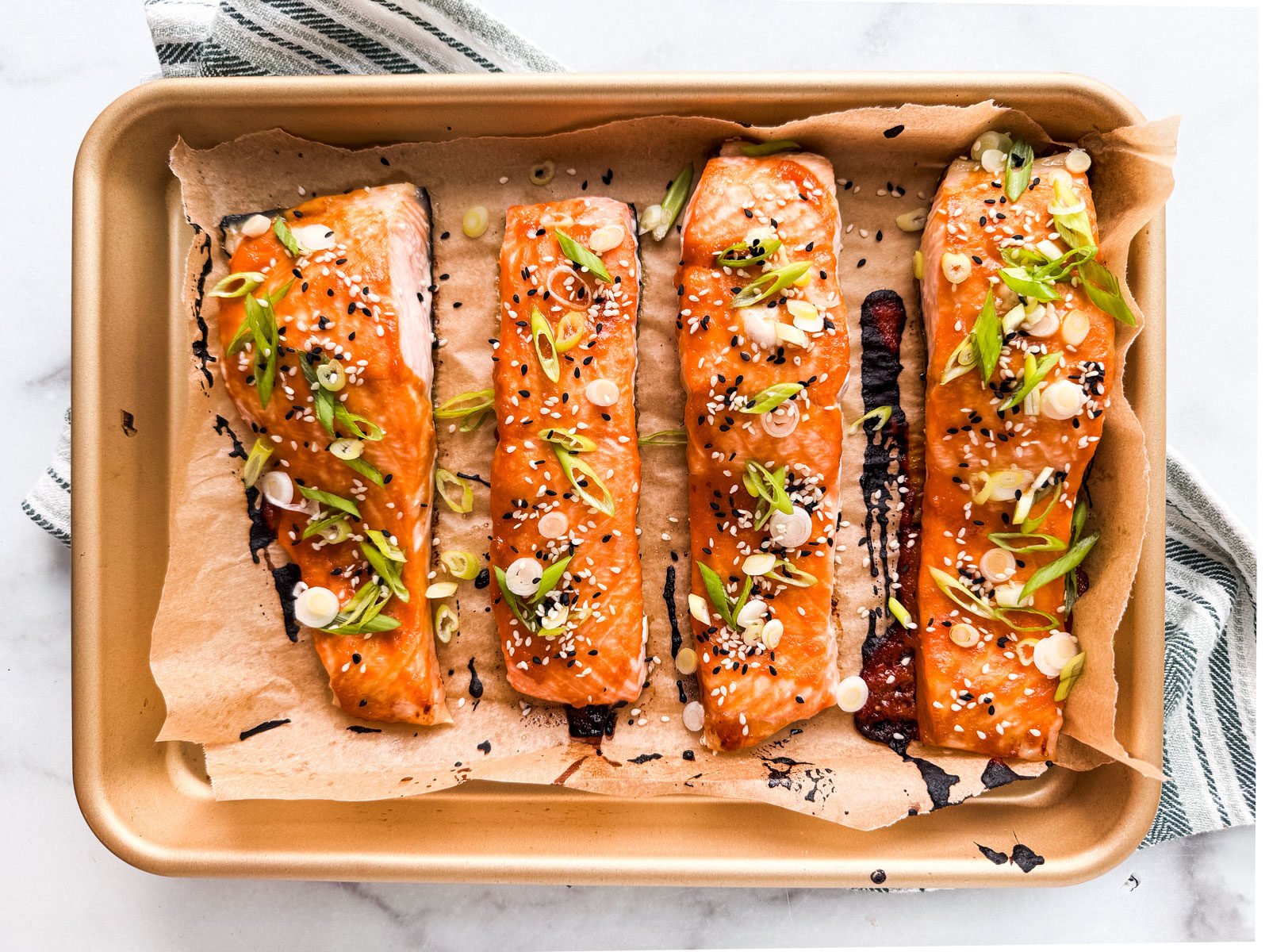 Cooked salmon fillets garnished with scallions and sesame seeds.