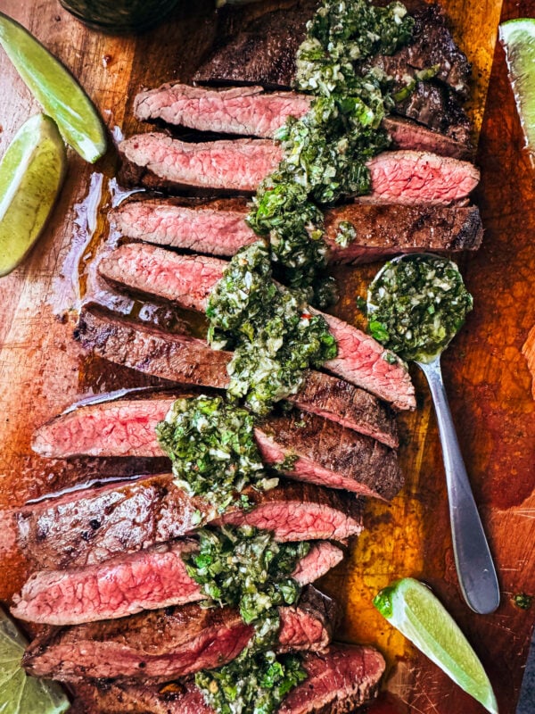 Medium-rare flank steak slices drizzled with chimichurri.