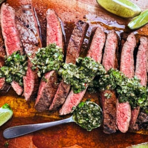 Medium-rare flank steak slices drizzled with chimichurri.