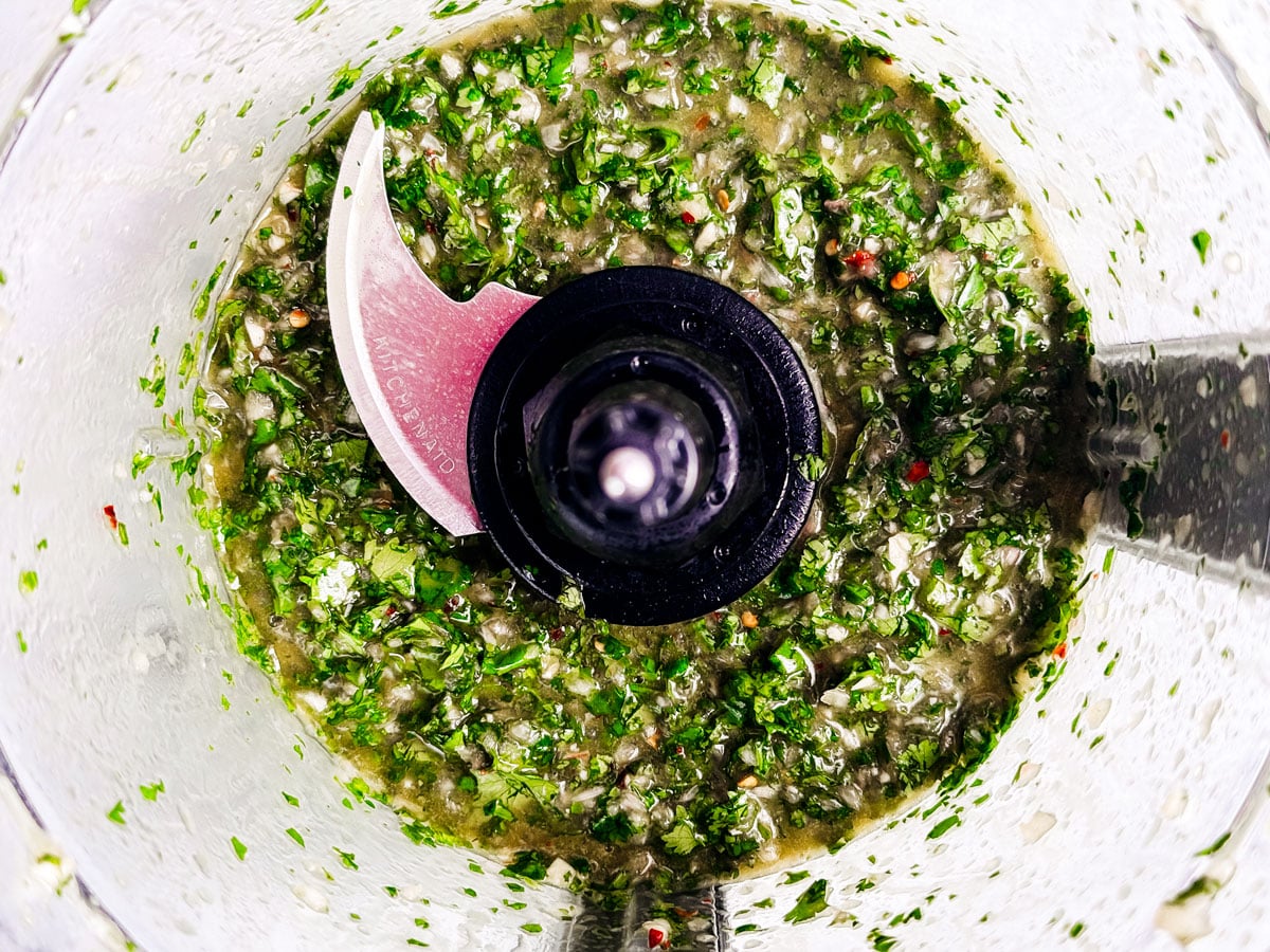 Blended chimichurri in a food processor bowl.