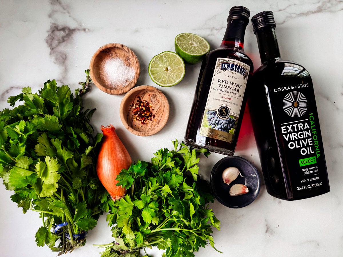 Ingredients for chimichurri spread out on a marble countertop.