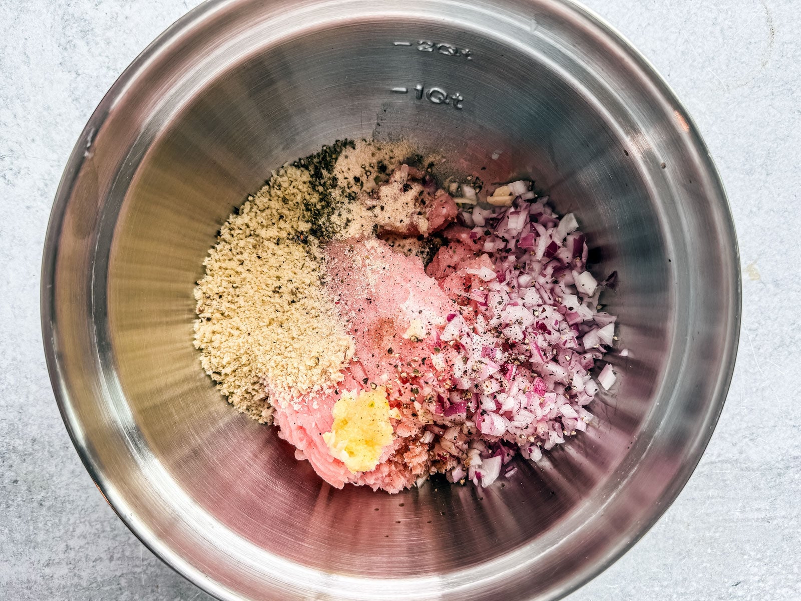 Mixing bowl with ingredients for turkey burger patty in it.