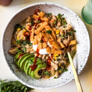 White Chicken Chili in a bowl topped with avocado and hot sauce.