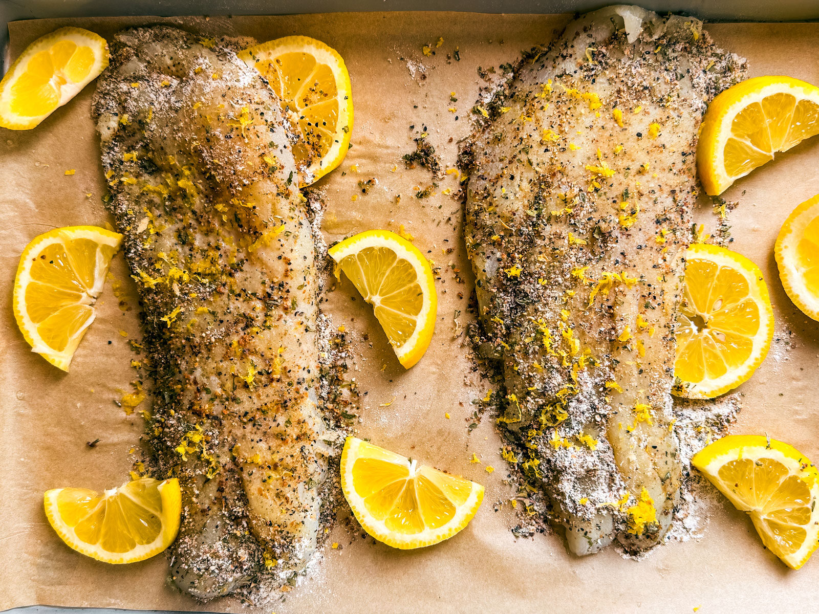 Seasoned uncooked grouper fillet on a baking sheet.