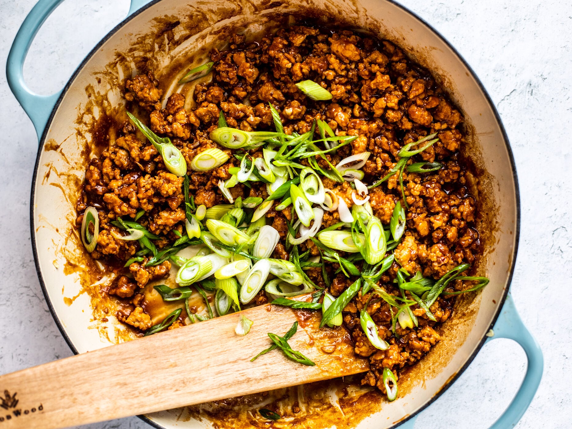 Skillet full of cooked hoisin sesame ground chicken and sliced scallions added.
