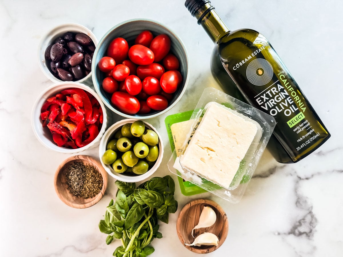 Ingredients for baked feta appetizer on a white marble countertop.