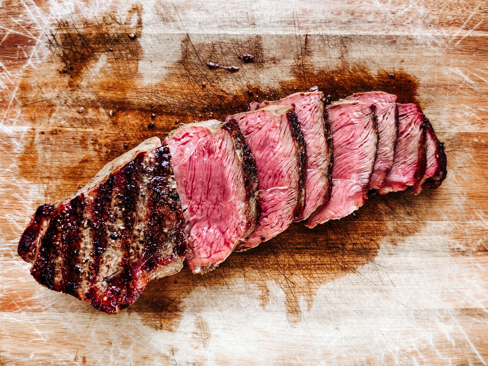 Sliced steak on a cutting board exposing a nice medium rare center.