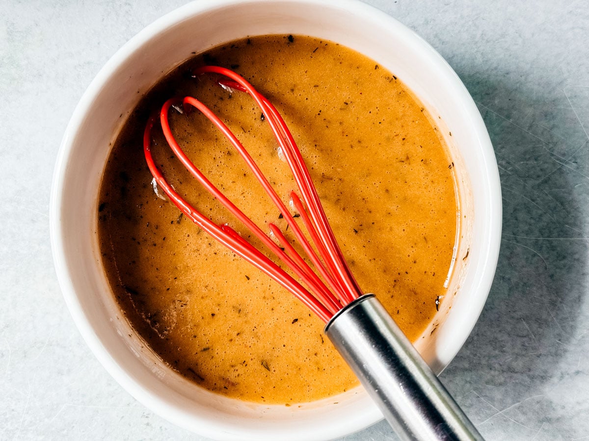 Red wine vinaigrette in a bowl with a whisk.