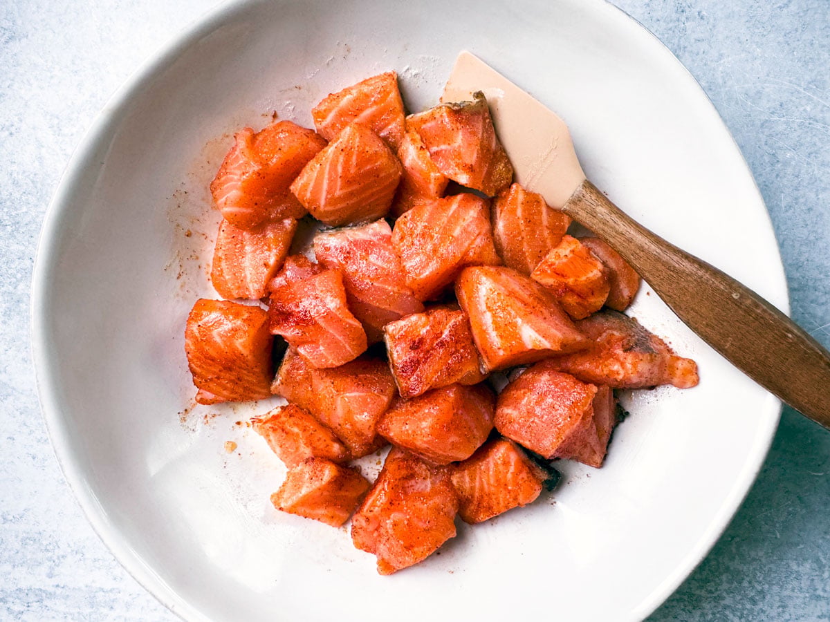 Seasoned salmon, uncooked, in a mixing bowl.