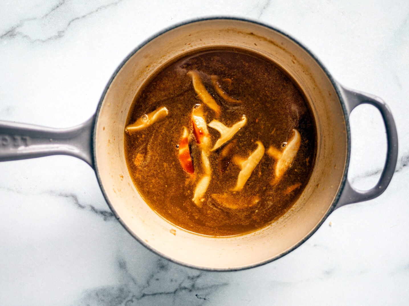 Broth with mushrooms in saucepan.
