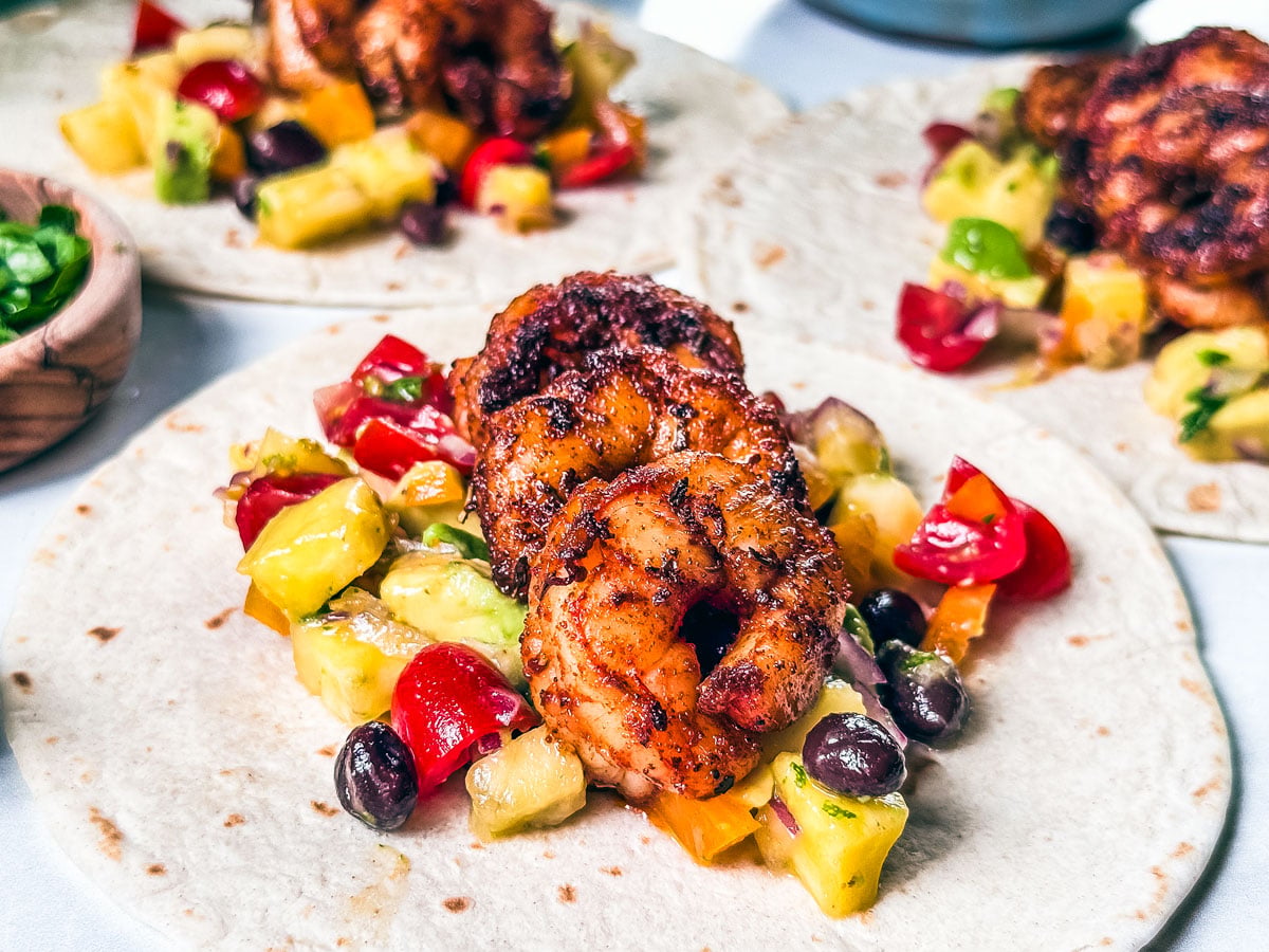 Blackened shrimp and pineapple avocado salsa on top of tortillas.