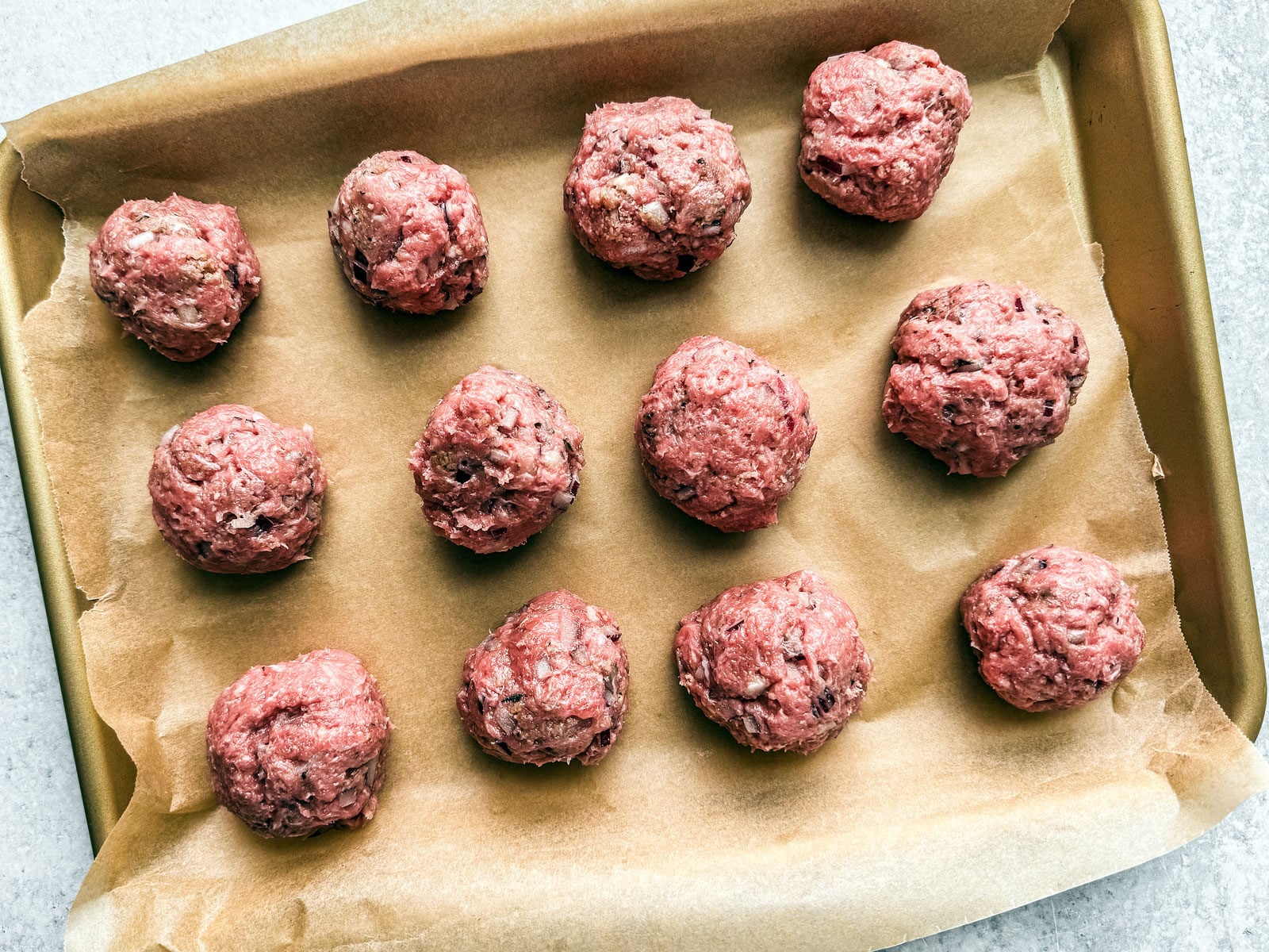 Ground turkey meatballs on a baking sheet.