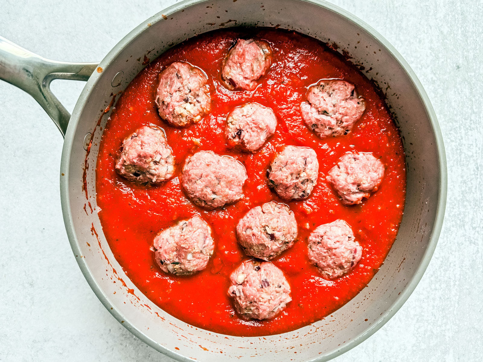Uncooked turkey meatballs in sauce.