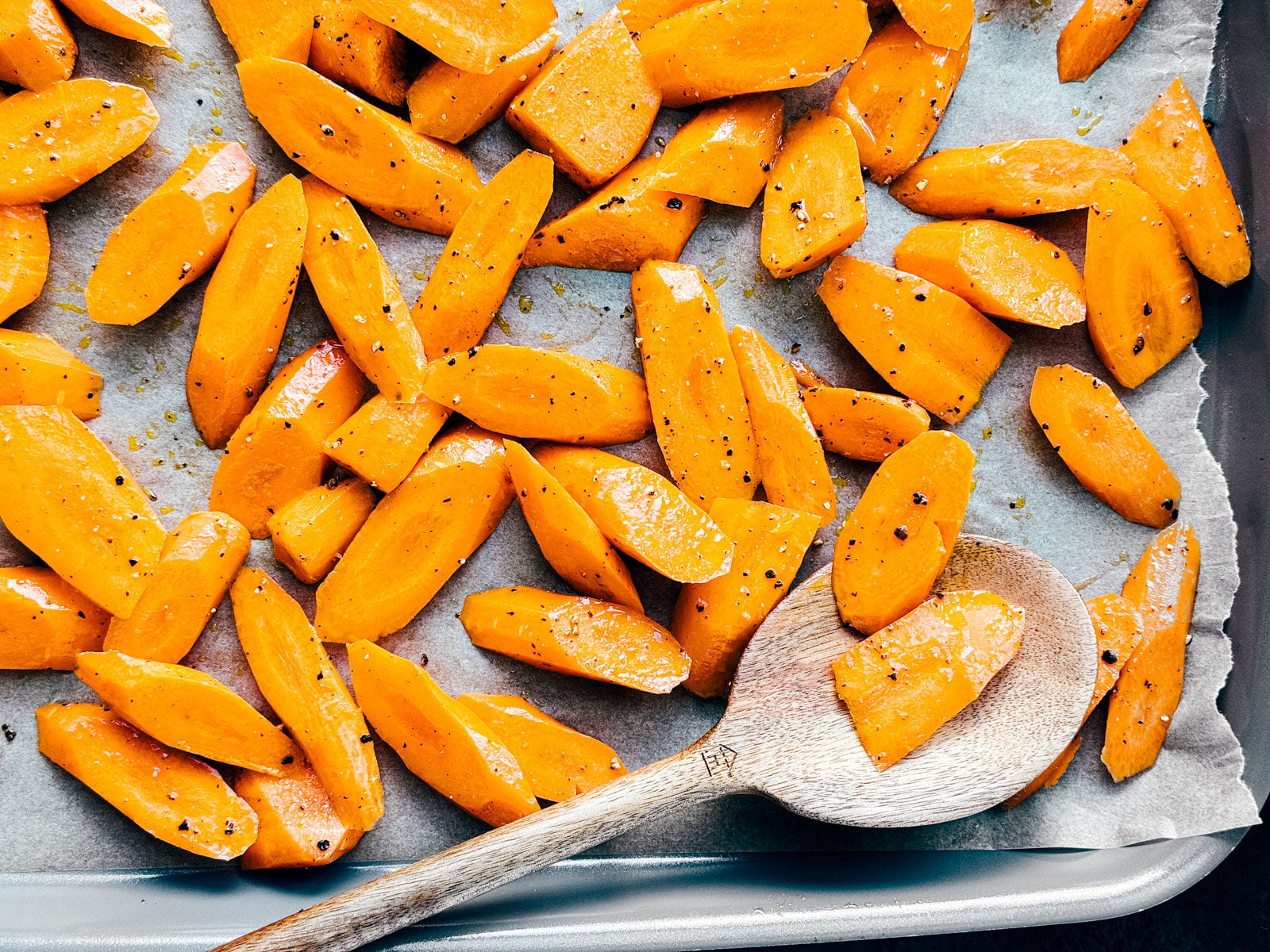 Sheet pan with carrots tossed in olive oil, salt, and pepper.