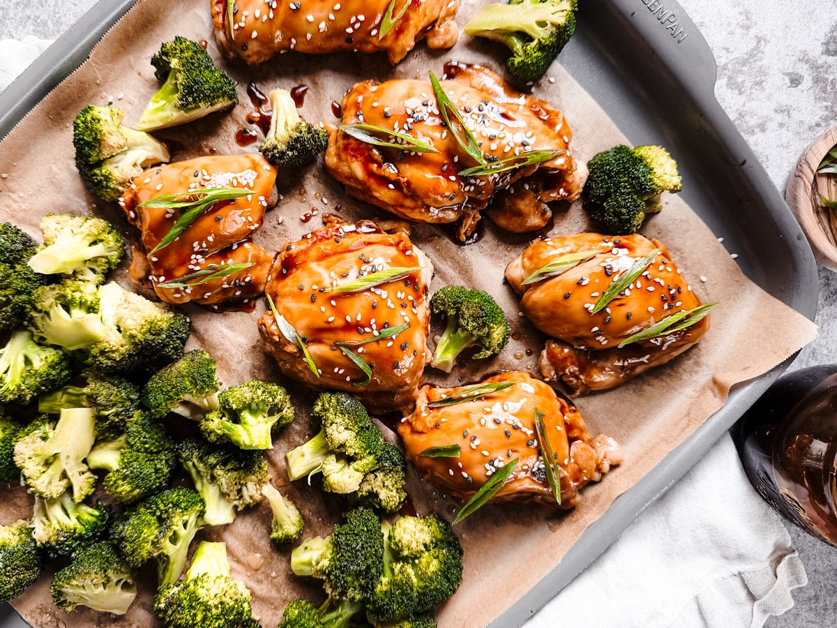 Sheet pan with teriyaki chicken thighs and broccoli florets.